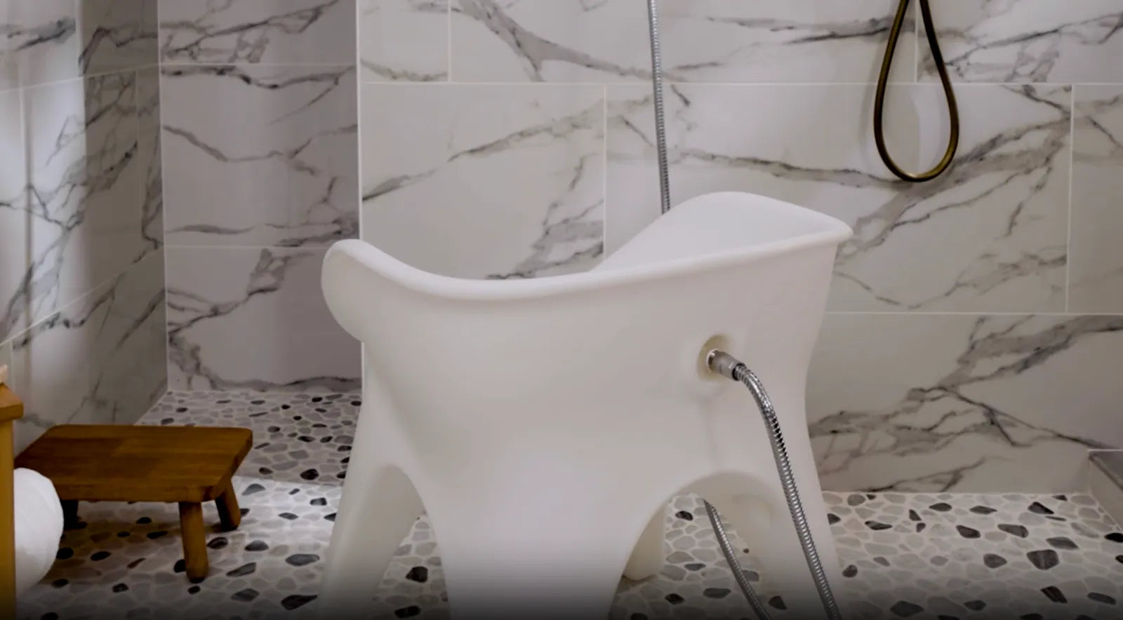 SoSoak shower & sitz bath chair in a marble shower with the hose connected